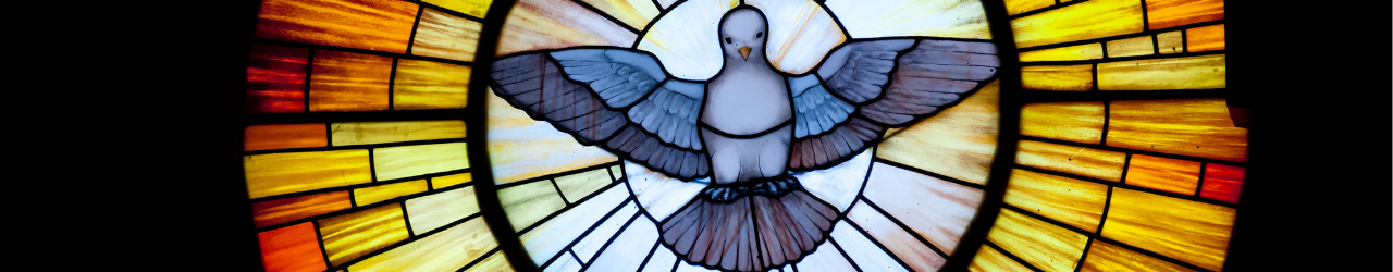 A stained glass window, with a dove descending through an orange and red circle.