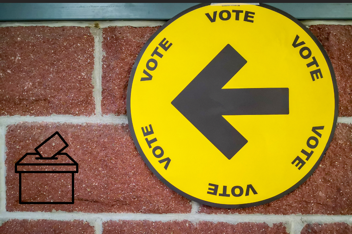 A bright yellow circle mounted on a brick wall, with a black arrow pointing left, and the word "Vote" repeated.